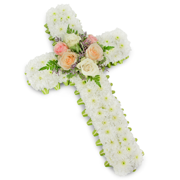 A thoughtfully designed floral cross for a funeral or memorial service is shown against a bright, uncluttered white background, with a gentle drop shadow lifting it forward so its structure is easy to read, much as it might appear standing beside the lectern in a Tulse Hill church. The cross follows the traditional Latin form, its arms and vertical stem built up from a solid base and then completely covered with compact white button chrysanthemums. Each bloom is placed so closely that the flowers form a continuous, velvety carpet of white, creating a sense of calm, order, and purity. The texture invites the imagination to feel the coolness of the petals and the faint, crisp scent that often fills the workshop at Florist Tulse Hill on an early delivery morning. Along the very edge of the design, a narrow band of lime green ribbon encircles the cross, offering a clean, tailored outline. This vivid but restrained green accent, reminiscent of newly unfurled leaves along Tulse Hill's residential streets, subtly sharpens the cross's silhouette without overpowering the white flowers. At the junction where the arms meet the upright, a central posy of roses adds gentle colour and emotional depth. Several fully open roses in soft pastel pink, creamy white, and delicate peach are nestled together, their layered petals surrounded by wispy fern fronds and small, starry lavender and light purple filler flowers. These details bring movement and contrast, like soft conversation in a quiet room of mourners. The arrangement, with its careful craftsmanship and balanced palette, serves as a deeply respectful expression of sympathy and Christian faith, suitable for services, crematorium chapels, or gravesides around Tulse Hill and the wider South London community.